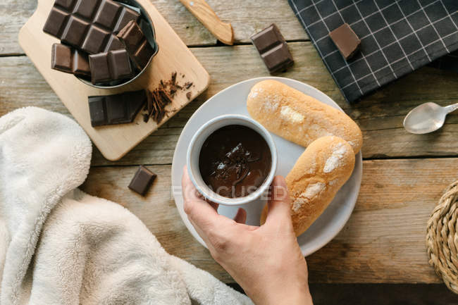 Human hand holding hot chocolate cup with chocolate chunks topping — Stock Photo