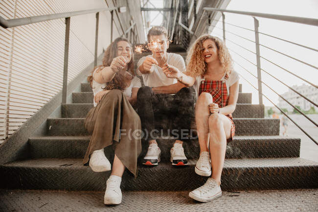 Friends with sparkles on steps — Stock Photo