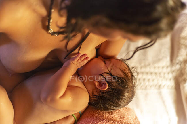 Crop donna allattamento al seno bambino sul letto — Foto stock
