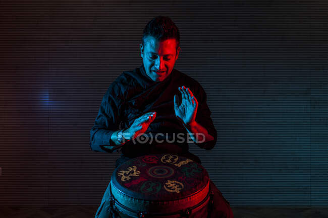Giovane percussionista pratica tecnica con tam tam o tamburo, illuminazione colorata in rosso e blu. — Foto stock