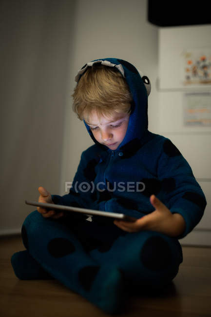 Маленький хлопчик дивиться мультфільми з цифровим планшетом на дерев'яній підлозі — стокове фото