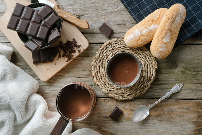 Чашка горячего шоколада с кусочками шоколада на деревянном столе — стоковое фото