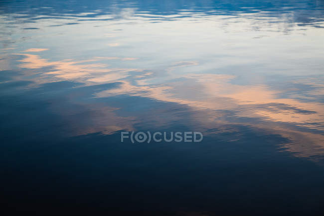 Спокійна вода озера з відображенням заходу сонця неба на поверхні — стокове фото