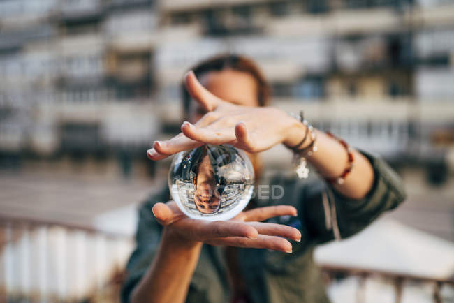 Mulher segurando bola de cristal com reflexão na cidade — Fotografia de Stock