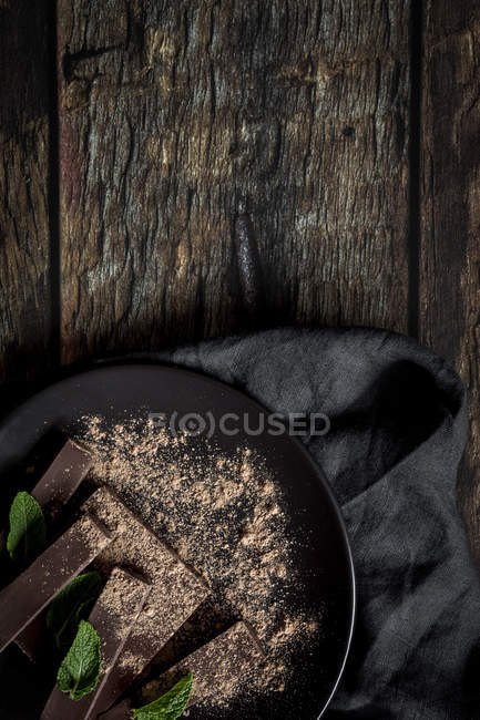 Pedaços de chocolate e pedaços com hortelã no fundo de madeira escura — Fotografia de Stock