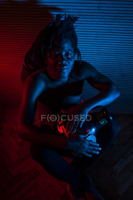 Junger afrikanischer rastafarian mann probt gerne und spielt udu, farbige beleuchtung rot und blau — Stockfoto