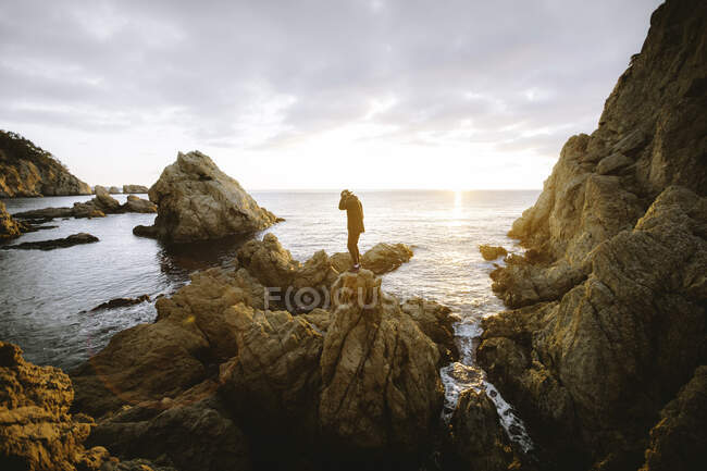 Persona irreconocible de pie en el acantilado cerca del mar - foto de stock