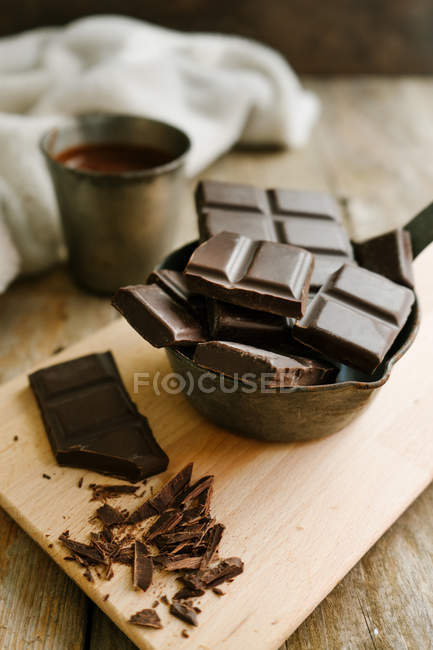 Morceaux de chocolat noir sur planche à découper en bois — Photo de stock