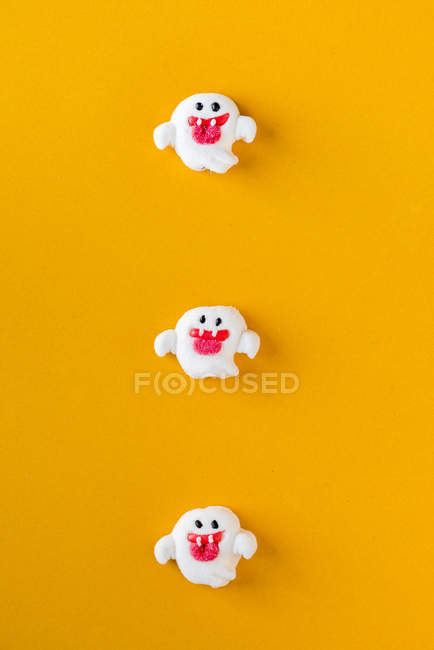 Doces de Halloween em forma de fantasma no fundo laranja — Fotografia de Stock
