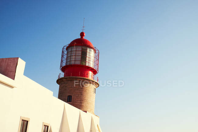 Красный маяк и белое здание — стоковое фото