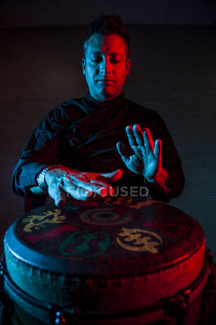 Jovem percussionista praticando técnica com o tam tam ou tambor, iluminação colorida em vermelho e azul. — Fotografia de Stock