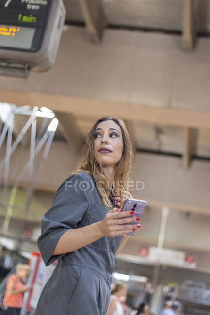 Mulher usando smartphone na estação ferroviária — Fotografia de Stock