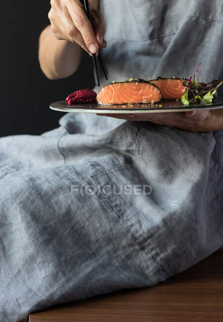 Woman talking delicious salmon fillets with chopsticks — Stock Photo