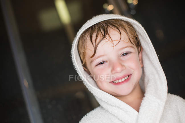 Portrait de petit garçon souriant aux cheveux mouillés en peignoir — Photo de stock