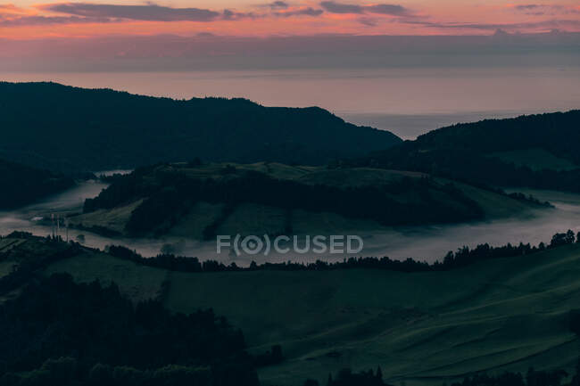 Crater of Azores surrounded by mountains on background of evening sky colored in purple — Stock Photo