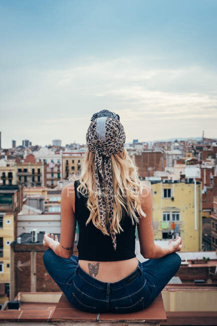 Jeune femme assise sur le toit — Photo de stock