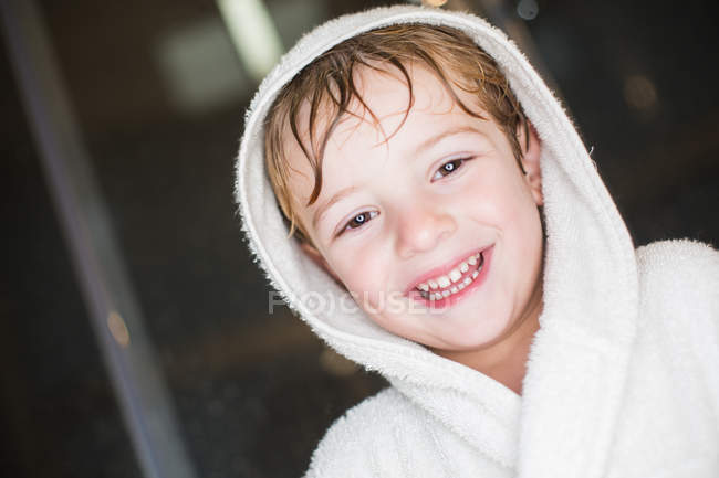 Portrait de petit garçon souriant aux cheveux mouillés en peignoir — Photo de stock