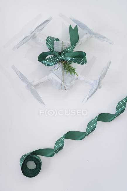 Drone embrulhado como presente de Natal com fita verde no fundo branco — Fotografia de Stock