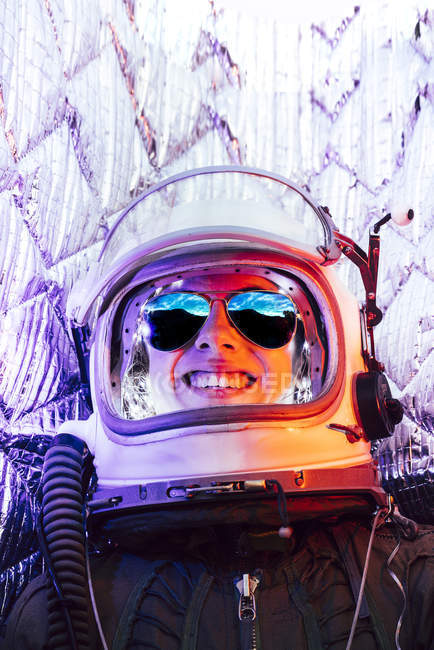 Niña riendo usando casco espacial viejo contra fondo de papel de aluminio - foto de stock