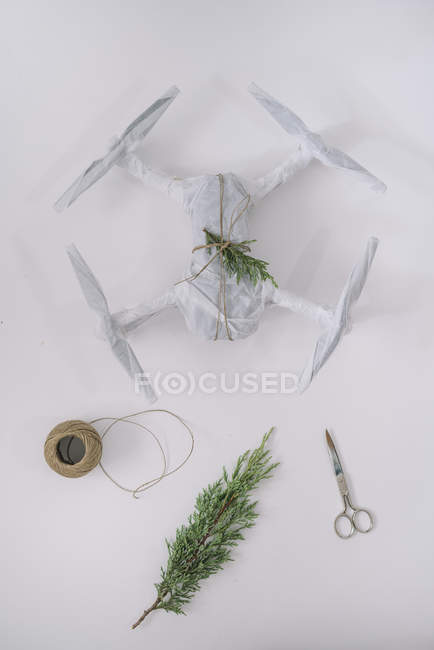 Drone envuelto como regalo de Navidad con rama de abeto y cordel sobre fondo blanco - foto de stock
