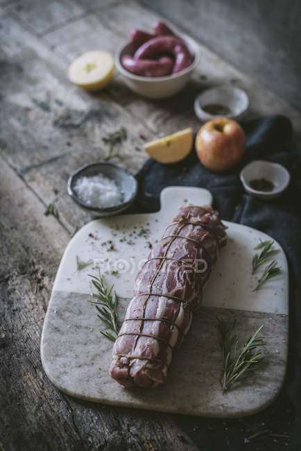 Свиная вырезка на деревянном столе со специями и ингредиентами — стоковое фото