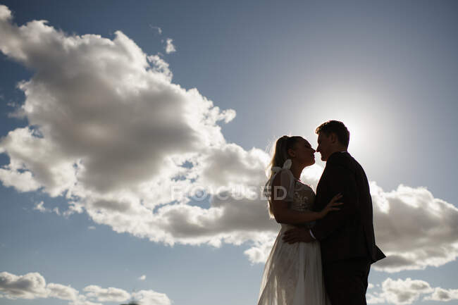 Знизу подружня пара надувається і обіймається на тлі хмарного блакитного неба — стокове фото