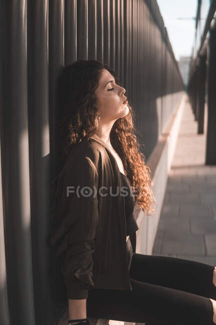 Giovane donna godendo di sole vicino alla recinzione — Foto stock