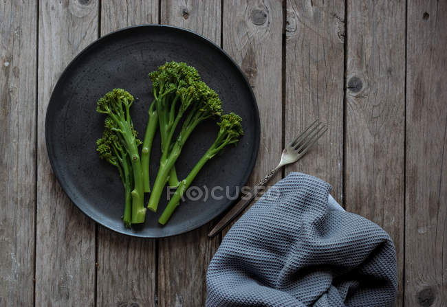 Steamed broccoli on black plate on wooden table — Stock Photo