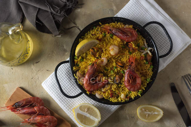 Paella marinera tradicional española con arroz, gambas, calamares y mejillones en sartén con ingredientes - foto de stock