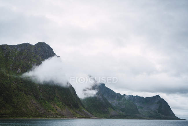 Rivière coulant près des montagnes couvertes de nuages — Photo de stock