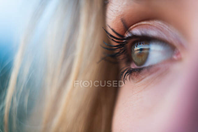 Crop view of woman face with blond hair and green eye looking aside — Stock Photo