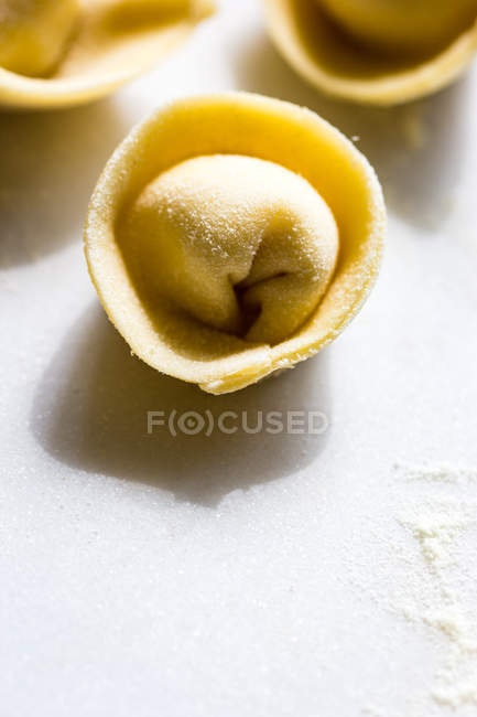 Primer plano de tortellini sin cocer sobre mesa blanca - foto de stock