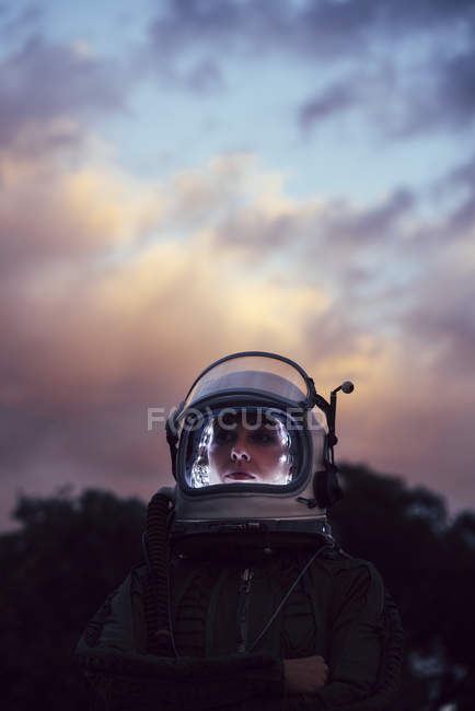 Дівчина в старому космічному шоломі і космічному кораблі проти драматичного неба на заході сонця — стокове фото