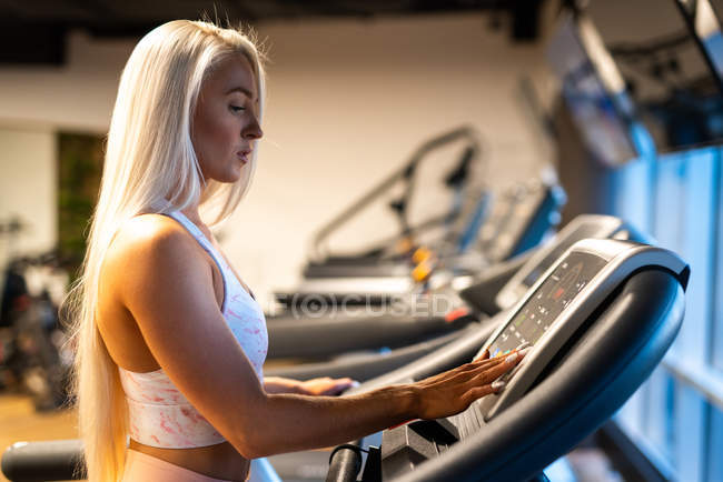 Блондинка молода жінка тренується на біговій доріжці — стокове фото