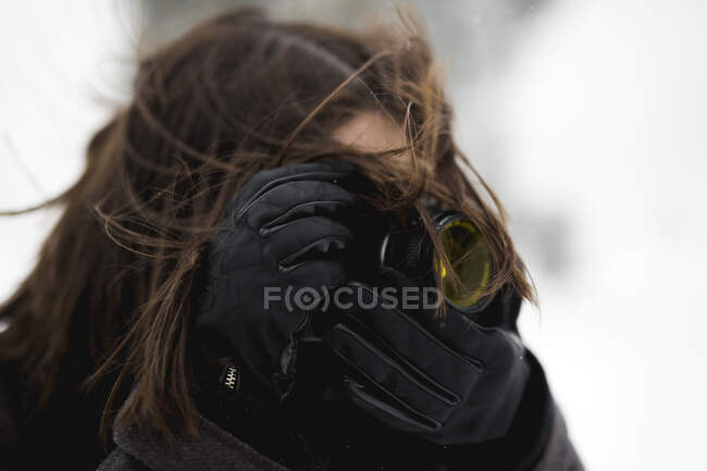 Анонимная женщина в теплых перчатках с помощью профессиональной камеры снимает в ветреный зимний день — стоковое фото