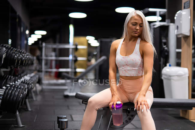 Junge Sportlerin ruht sich in Turnhalle mit Trinkwasser aus — Stockfoto