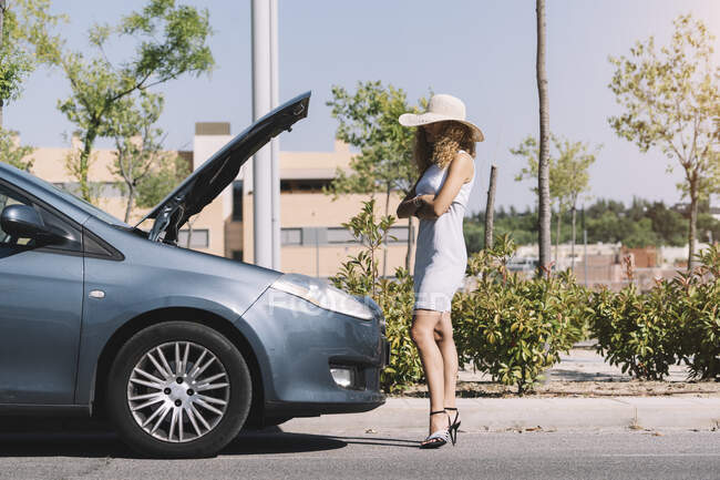 Girl standing in front of her broken car — Stock Photo