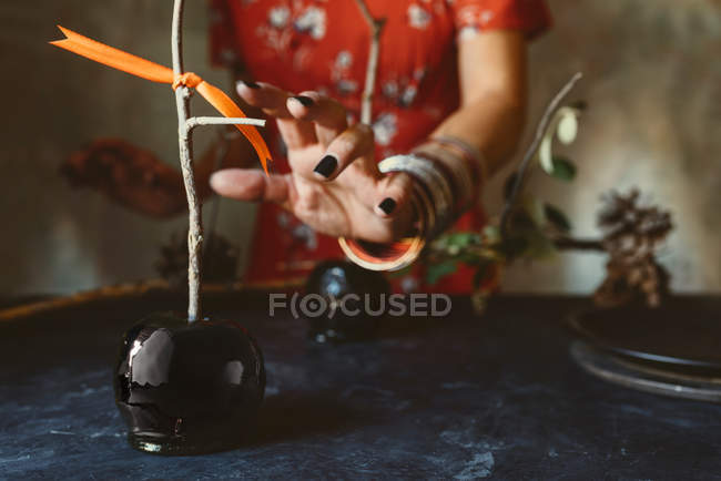Mão feminina tomando maçã caramelizada preta para o dia das bruxas — Fotografia de Stock
