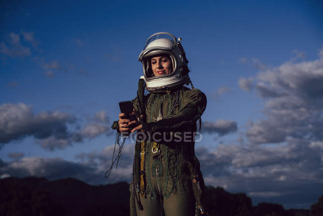 Улыбающаяся женщина-астронавт делает селфи мобильный телефон в вечерней природе — стоковое фото