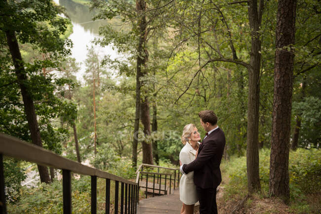 Зверху знімок захоплення дорослої нареченої і нареченої, що стоїть на дерев'яній доріжці в зеленому лісі — стокове фото