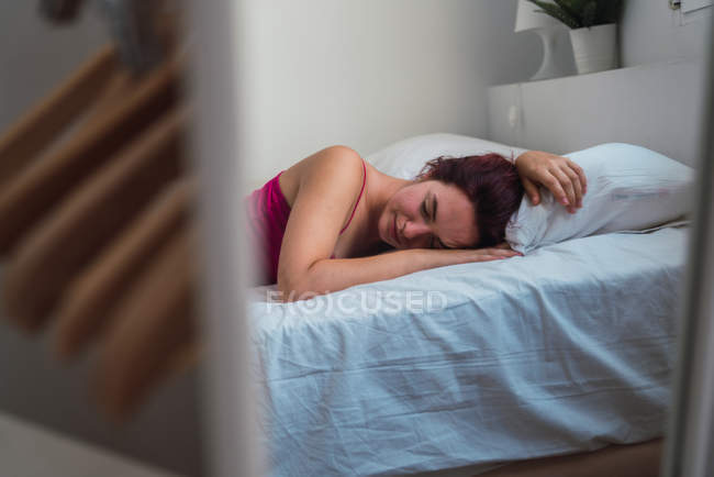 Jovem mulher relaxada deitada na cama com os olhos fechados — Fotografia de Stock