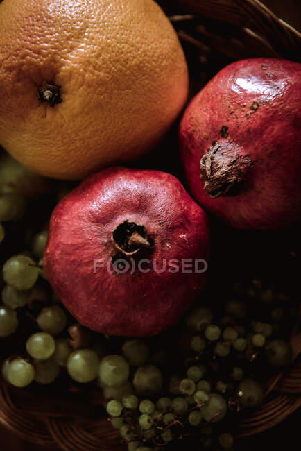 Корзина с апельсинами, виногранатами и гранатами на столе — стоковое фото