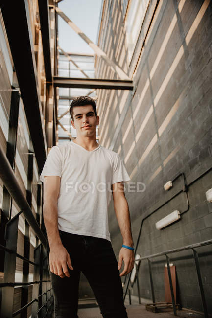 Portrait de jeune homme beau debout dans un bâtiment de construction et regardant la caméra — Photo de stock
