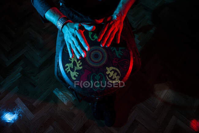 Молодий ударник, який практикує техніку з тамаром або барабаном, кольорове освітлення в червоному і синьому. рук дивитися — стокове фото