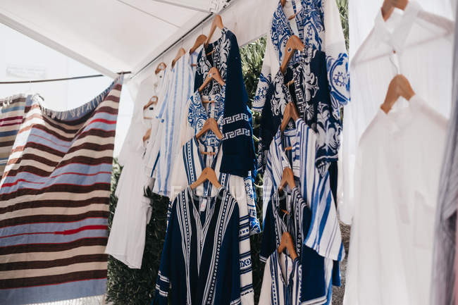 Different traditional tunics on cloth hangers at street market, Mykonos, Greece — Stock Photo