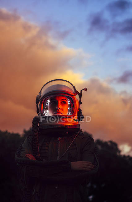 Ragazza che indossa il vecchio casco spaziale e tuta spaziale contro il cielo drammatico al tramonto — Foto stock