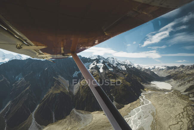 Vista de montañas nevadas bajo el ala del avión - foto de stock