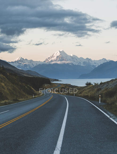 Strada asfaltata tortuosa che conduce alla maestosa montagna Aoraki in una bellissima serata nuvolosa in Nuova Zelanda — Foto stock