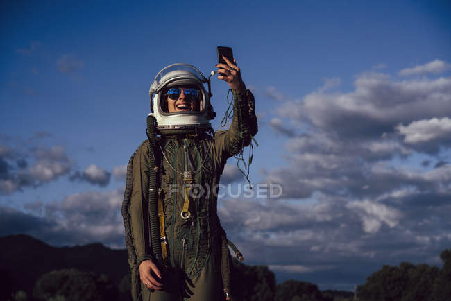 Sorridente astronauta donna scattare selfie cellulare in natura sera — Foto stock