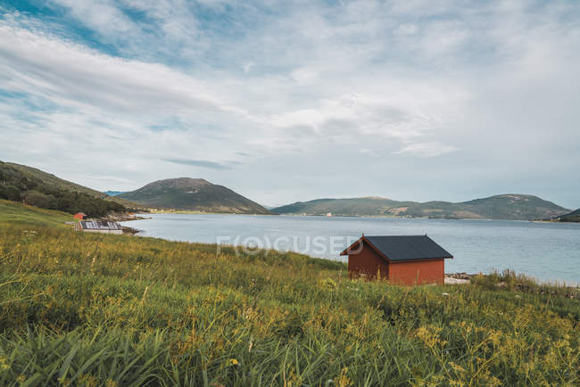 Maison isolée en bois près de la mer et des montagnes dans un ciel couvert — Photo de stock